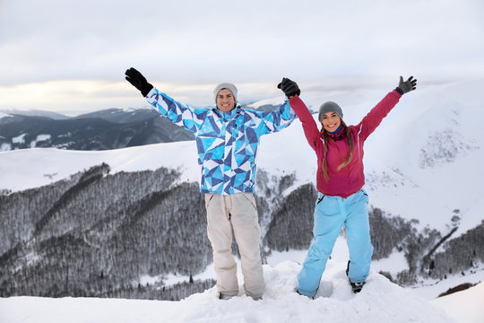 Happy couple on snowy mountain peak at resort. Winter vacation