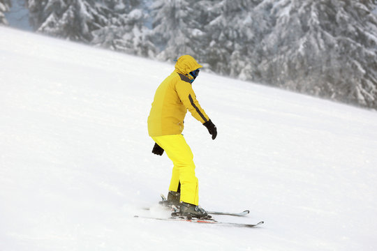 Man skiing downhill at snowy resort. Winter vacation