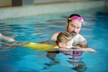 Happy father teaching his little daughter to swim. Active happy child learning to swim.