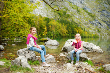 Naklejka premium Little girls enjoying the view of deep green waters of Obersee, located near Konigssee, known as Germany's deepest and cleanest lake, Germany