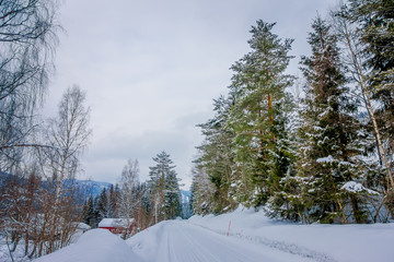 Outdoor view of winter road covered with snow and ice in the forest of Norway