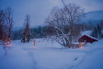 Amazing night view of traditional wooden houses with snow in the roof in stunning nature background, with some lights and posts at outdoors in Valdres region in Norway