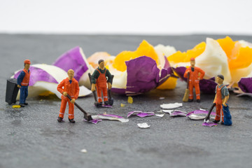 miniature worker people working on egg