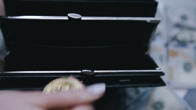 Close up of female hand puts golden bitcoins into a wallet