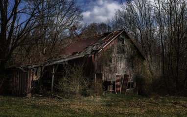 Fototapeta na wymiar An abandoned, decaying barn in a rural area. 