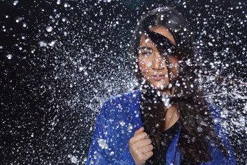 Active Woman rain coat with Water Splash over studio lighting black backgrounds