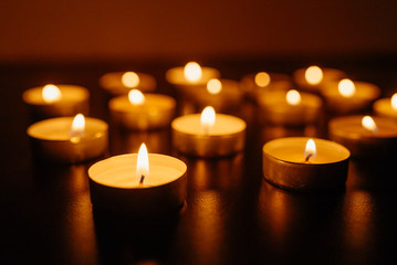 Fototapeta na wymiar Kemerovo, Russia, fire in the mall, burning candles. Shallow depth of field. Many candles burning at night. Candles background. Many candle flames glowing on dark background. Close-up. Free space.