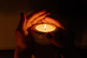 Kemerovo, Russia, fire in the mall, burning candles. Candle in female hands on black background. Many candles burning at night. Many candle flames glowing on dark background. Close-up. Free space.