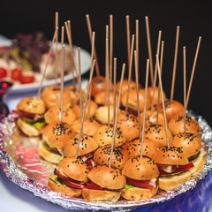 Beautifully decorated catering banquet table with different hamburgers burgers sandwiches on a plate on corporate christmas birthday party event or wedding celebration