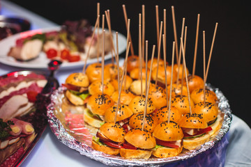 Beautifully decorated catering banquet table with different hamburgers burgers sandwiches on a plate on corporate christmas birthday party event or wedding celebration