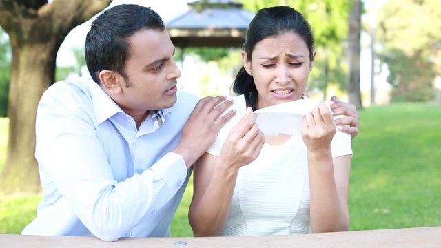 Closeup portrait of young man in blue shirt trying to console woman in distress isolated outdoors outside background