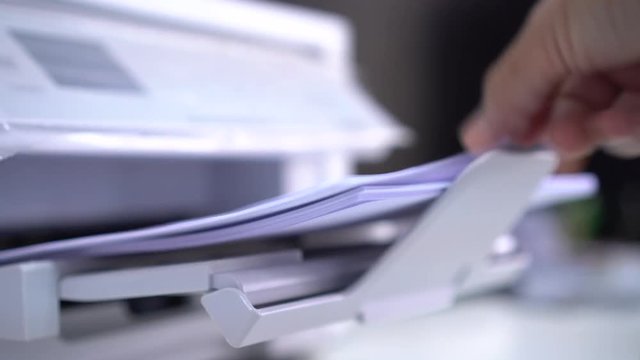 Business office Concept : Hand Businessman is process of press paper on laser print cartridge, lay down or take papers from printer at Busy Offices background
