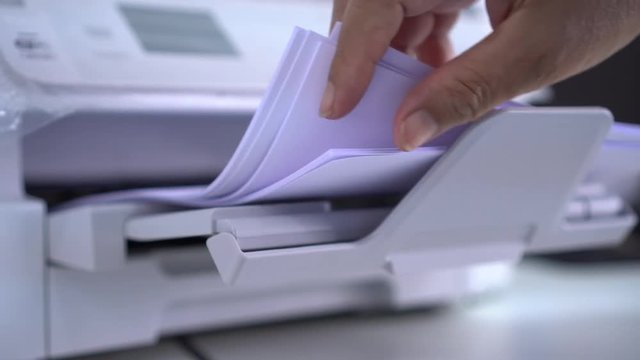 Business office Concept : Hand Businessman is process of press paper on laser print cartridge, lay down or take papers from printer at Busy Offices background