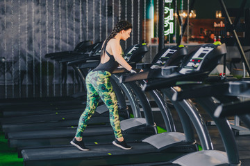 Obraz premium Attractive young fitness model runs on a treadmill, is engaged in fitness sport club