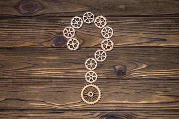 the question mark is assembled from gears. natural wood background. Business concept idea, puzzle, strategy.
