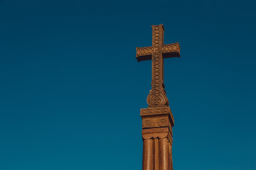 Stone cross khachkar of Khor Virap Monastery against blue sky. Religious landmark. Copy space for text. Religion symbol. Carved christian cross. Faith concept