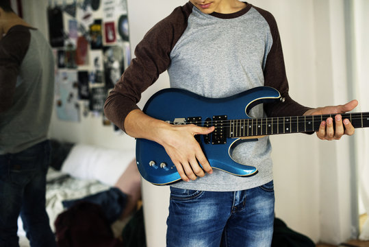 Teenage boy playing an electric guitar in a bedroom hobby and music concept