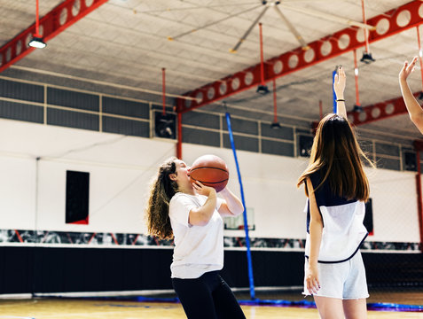 Teenage girl playing a basketball making a pass