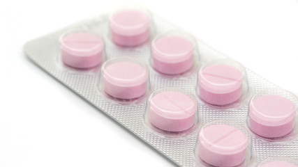 Pink pill on a white background, selective focus.