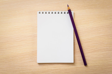 Purple pencil with notebook on wooden table