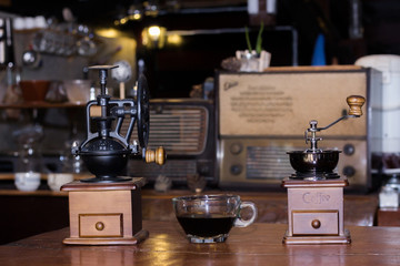 Coffee grinders and black coffee cups are on the table.