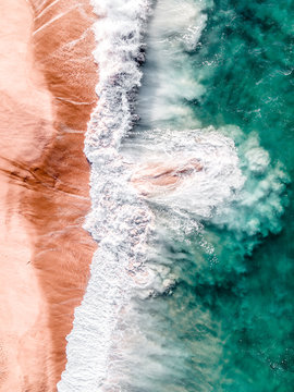 Aerial view of colorful waves crashing in sea