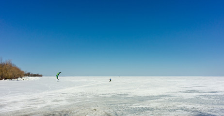 Fototapeta na wymiar Kite surfer on skis on a frozen lake.
