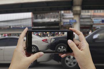 Hand holding smart phone take a photo at The scene of a car crash