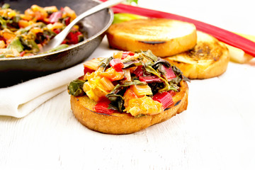 Bruschetta with chard and orange on light board