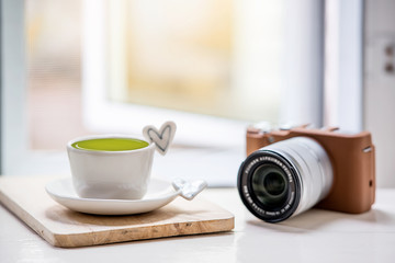 cup of green tea  and classic camera on white table