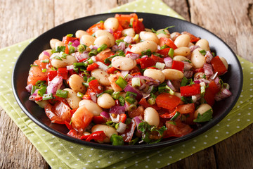 Homemade salad with beans, tomatoes, onions, peppers and herbs close-up on a plate. horizontal