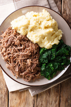 South African food: - Seswaa shredded beef with sadza porridge and spinach close-up on a plate. Vertical top view