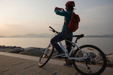 silhouette cyclist use mobile phone taking picture while riding bike in the sunrise coast road