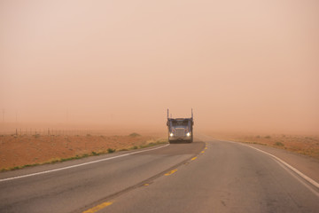Fototapeta na wymiar Big rig car hauler semi truck running on the Arizona road during huge sandstorm