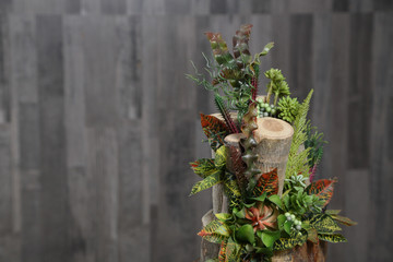 Floral arrangement of multicolored flowers, leaves and berries in wooden stump.