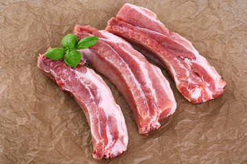 Raw fresh pork ribs and basil on the background of craft paper.