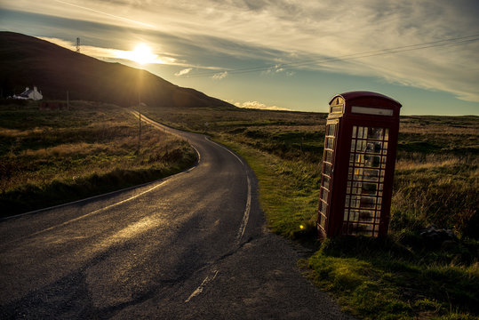 A lone telephone box stands on a road in the Scottish highlands