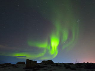 Northern lights, aurora over hills and tundra in the winter.