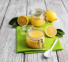 Lemon curd in glass jar with fresh lemons