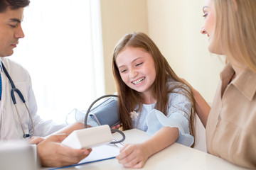 Doctor measuring blood pressure of girl patient at hospital. Healthcare and Medical concept.