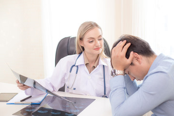 Fototapeta premium Attractive female doctor showing x-ray films to patient at clinic. Medical and Health care concept.