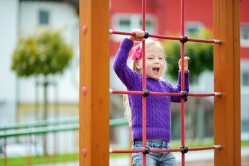 Obraz premium Cute little girl having fun on a playground outdoors in summer.