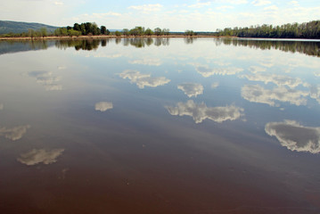 Spring landscape of the cloud pieces reflection in river surface. Wonderful picture