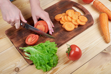 close up of female hand cutting tomato on cutting board at home, cooking, food and home concept