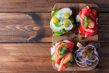 Smorrebrod, traditional Danish open sanwiches, dark rye bread with different topping, top view, copying space