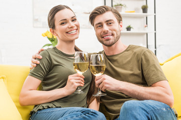 couple clinking with glasses of wine on couch at home