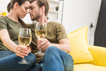 cuddling couple drinking wine together on couch at home