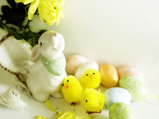 white bunny, yellow chickens and colorful eggs, copy space