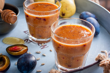 Fruity smoothies with a plum in glass glasses on a metal tray, horizontal