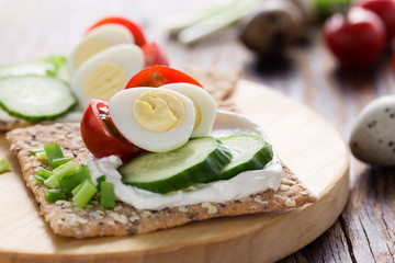 Chia seed crackers with cream cheese, cucumbers, tomato, quail egg and green onion